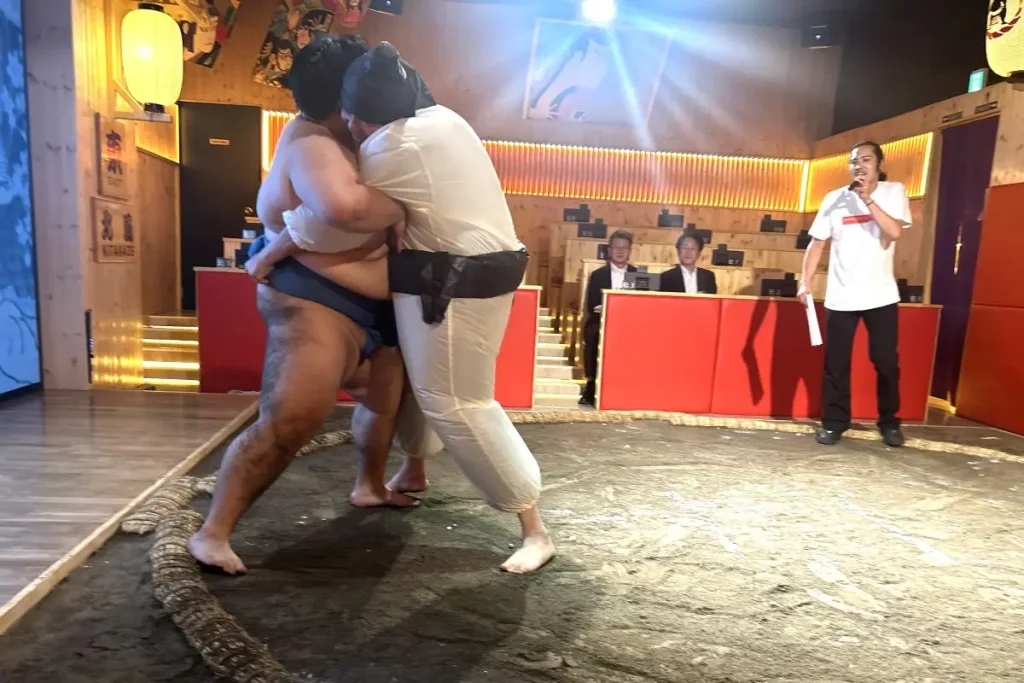 A close sumo match between the wrestler and the guest.