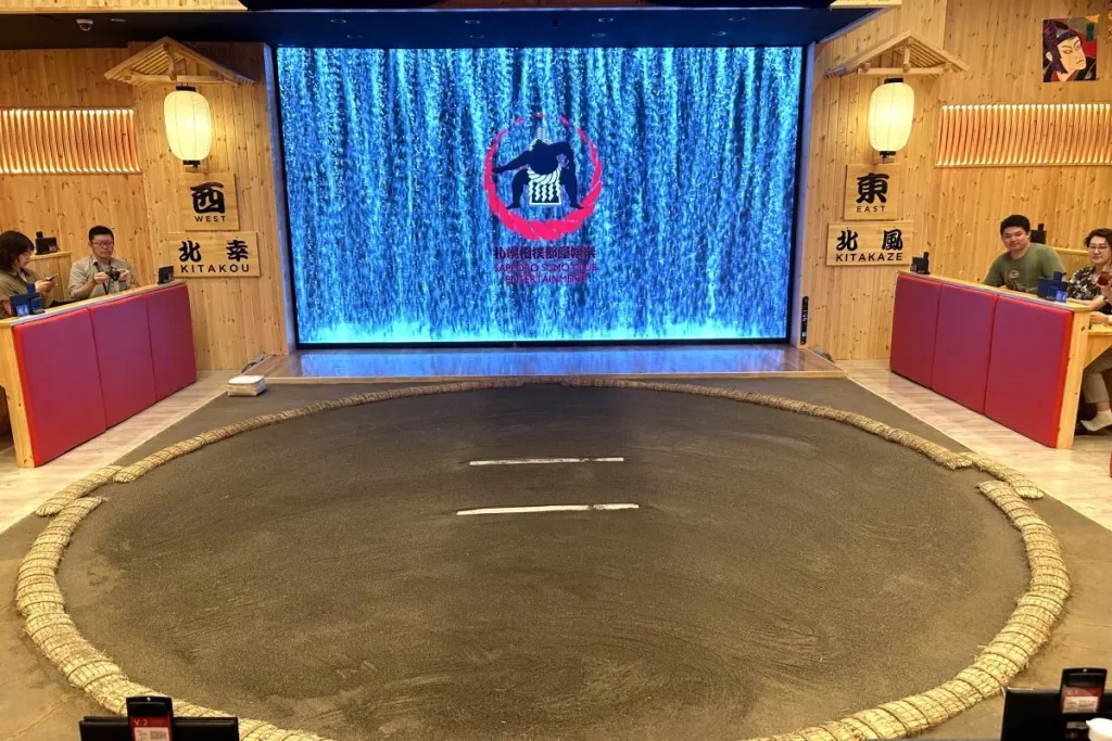 The circular dohyō (ring), built to the actual size used in professional tournaments, with a large screen displaying professional sumo match footage and other content.