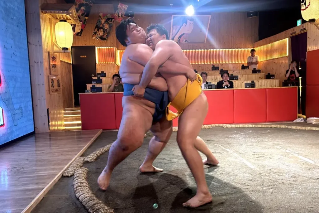 With the MC announcing, “Now it’s time for a sumo match,” a best-of-three match begins between the two wrestlers. Starting with rituals such as salt-throwing into the ring as part of the initial charge, each step is demonstrated with explanation: “Salt-throwing represents a way of purifying both the wrestlers as well as the ring.” As the match begins, the guests cheer enthusiastically, shouting the wrestlers’ names: “Go KITAKŌ!” and “Don’t lose, KITAKAZE!” The excitement fills the venue as each move draws gasps and applause from the guests.