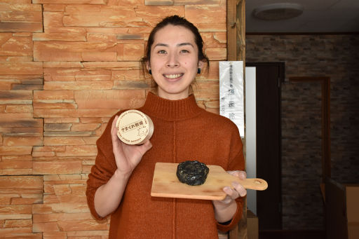 竹炭を使って開発した黒いチーズ「きまぐれ炭」を手にする開発者の勝長さん