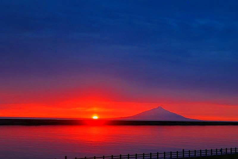 天塩川河川公園から臨む夕日に染まる天塩川（手前）と日本海に浮かぶ利尻富士