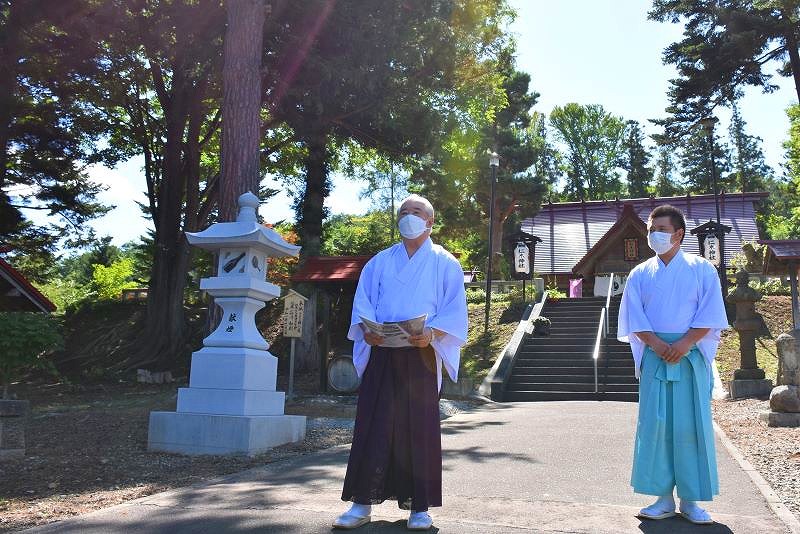 仁木神社の境内を案内する板谷宮司（左）