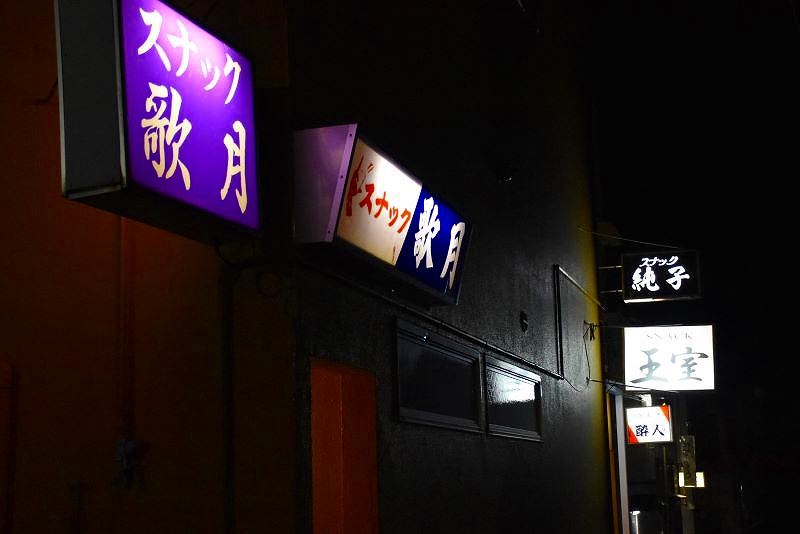 店の看板に明かりがともった雄武町のスナック街の様子