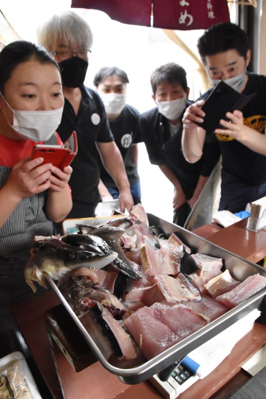 さばいたばかりのチョウザメを見て、調理方法のアイデアを出し合う北の屋台の店主ら