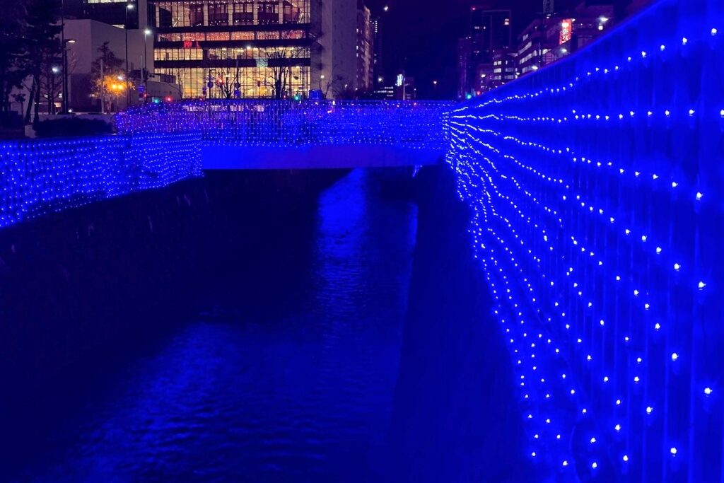 青色イルミネーションの光を受けてきらめく創成川の川面