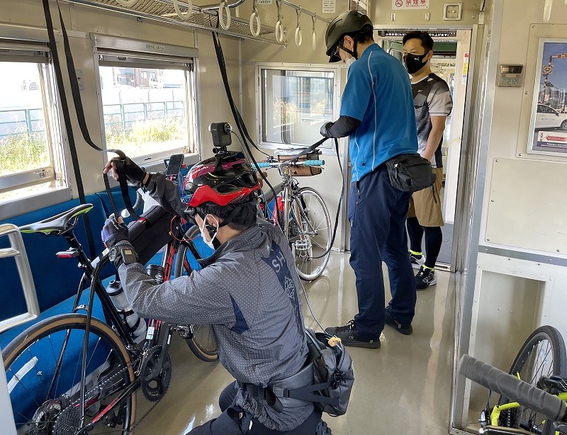 実証実験で列車内に持ち込んだ自転車を固定する参加者たち