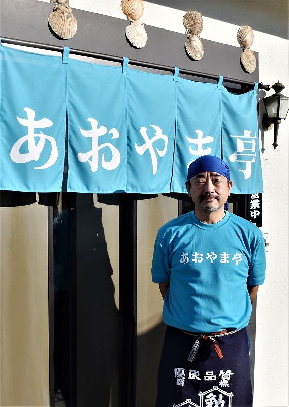 念願のラーメン店「あおやま亭」の店先に立つ、宮成隆弘さん