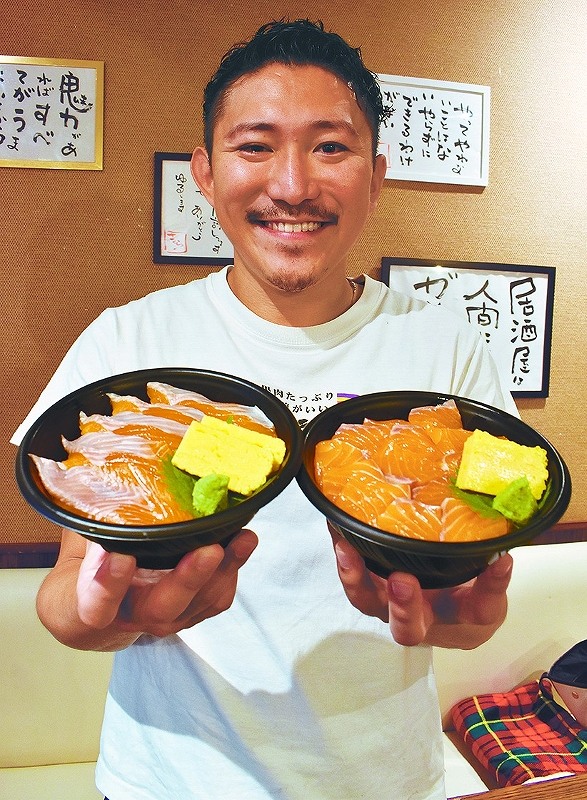 「サケカムイ」の店内で、提供している「蝦夷サーモン丼」（左）と「北海生とろサーモン丼」（右）を手にして紹介する代表の宇治康博さん