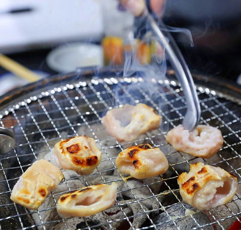 炭火の上の金網で焼かれている「焼肉ほりぐち」のホルモン