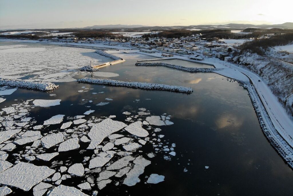 流氷に埋め尽くされた雄武町沿岸のオホーツク海と港の灯台
