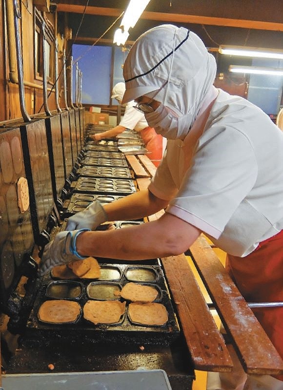 素早い動作でせんべいを焼き上げるタケダ製菓の従業員ら