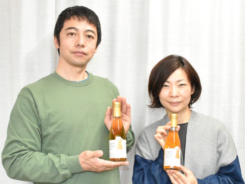 農林水産大臣賞受賞の「有機トマトジュースクリア」を手にする谷寿彰社長（左）と妻・江美さん