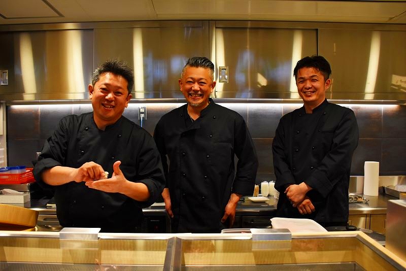 店頭で笑顔を見せる寿司「天金」の３人の従業員