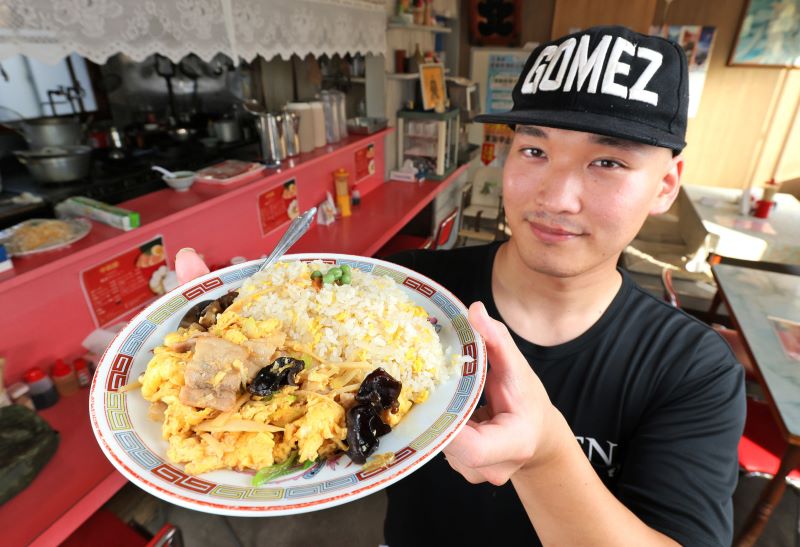 先代から受け継いだ名物のムースールー炒飯を手にする新店主の甲斐さん（藤井泰生撮影）