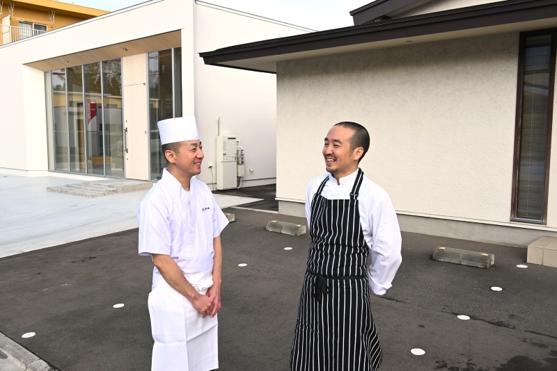 隣り合う店の前で談笑する松永さん（右）と大根田さん