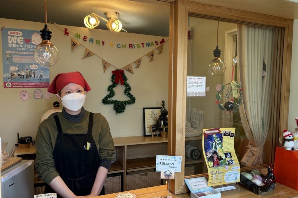 クリスマスの装飾をした「ももすず」の店頭に立つ駒形さん