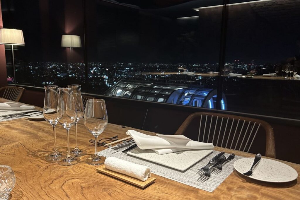 「ヌーベルプース大倉山」からの札幌の夜景の眺めと、グラスやカトラリーが並ぶテーブルイメージ