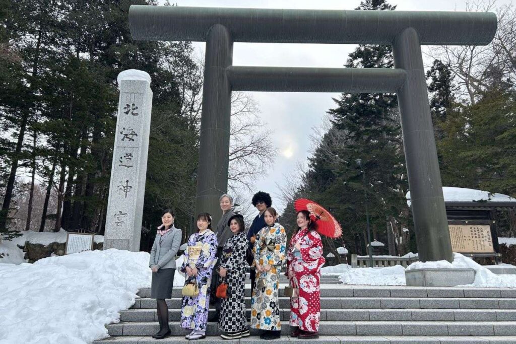 北海道神宮の鳥居の前で記念撮影する参加者