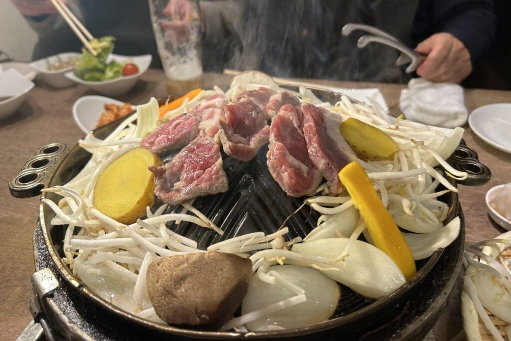 ジンギスカン鍋の上で野菜に囲まれるように、中央で焼かれる肉