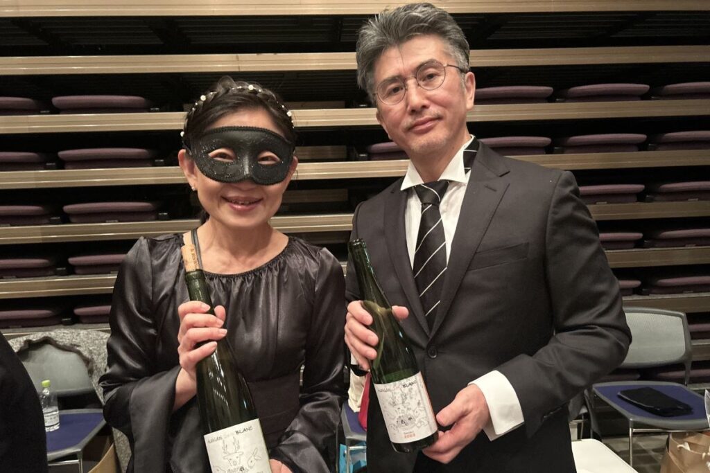 ワインボトルを手にする成田和仁さん、真奈美さん夫妻