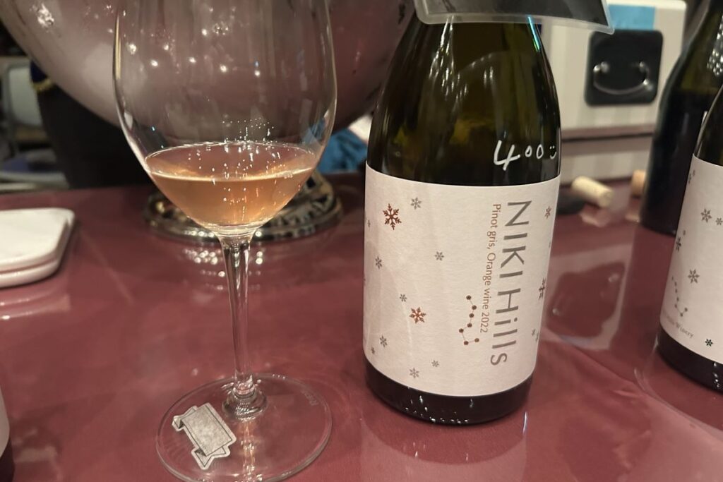 NIKI Hills wineryのオレンジワインのボトルと注がれたグラス