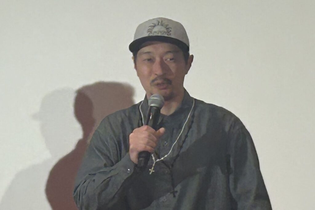 舞台でマイクを手に映画について語る綾部監督