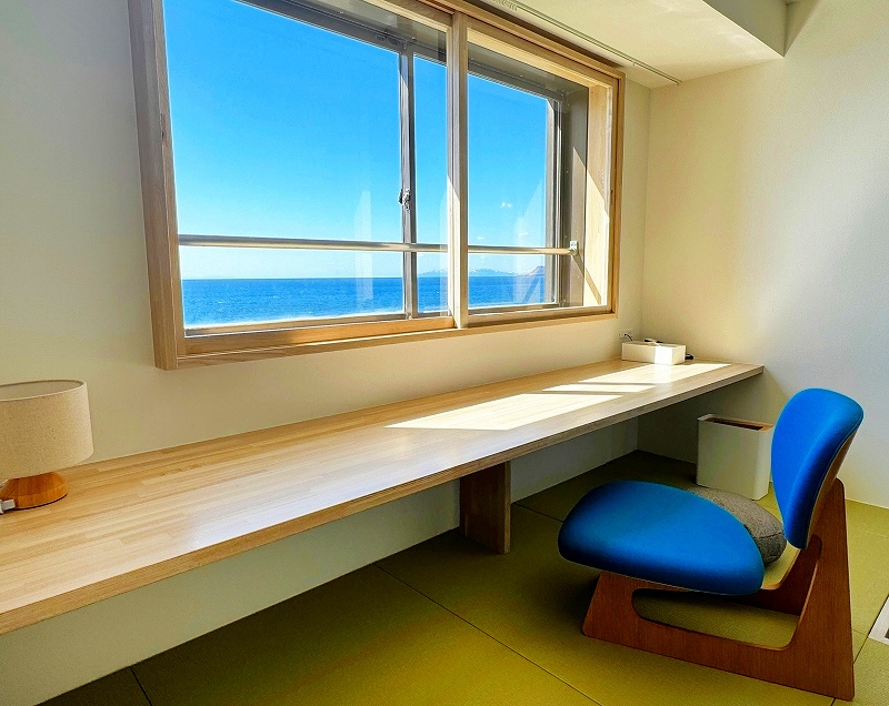 窓際のカウンターデスクから津軽海峡を一望できるワーケーション対応の客室（湯の浜ホテル提供）