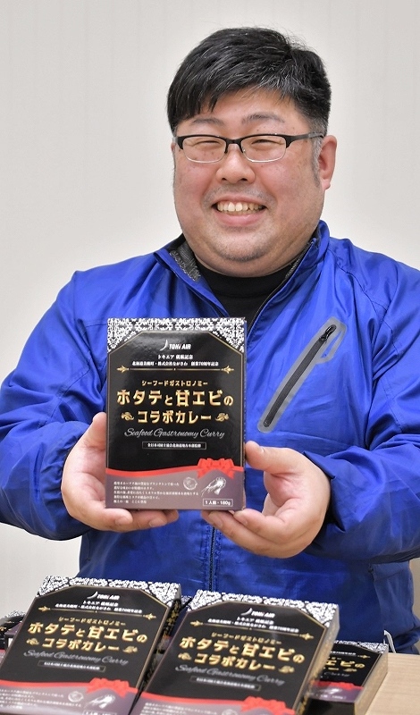 新商品「ホタテと甘エビのコラボカレー」を手にする永沢寛樹社長