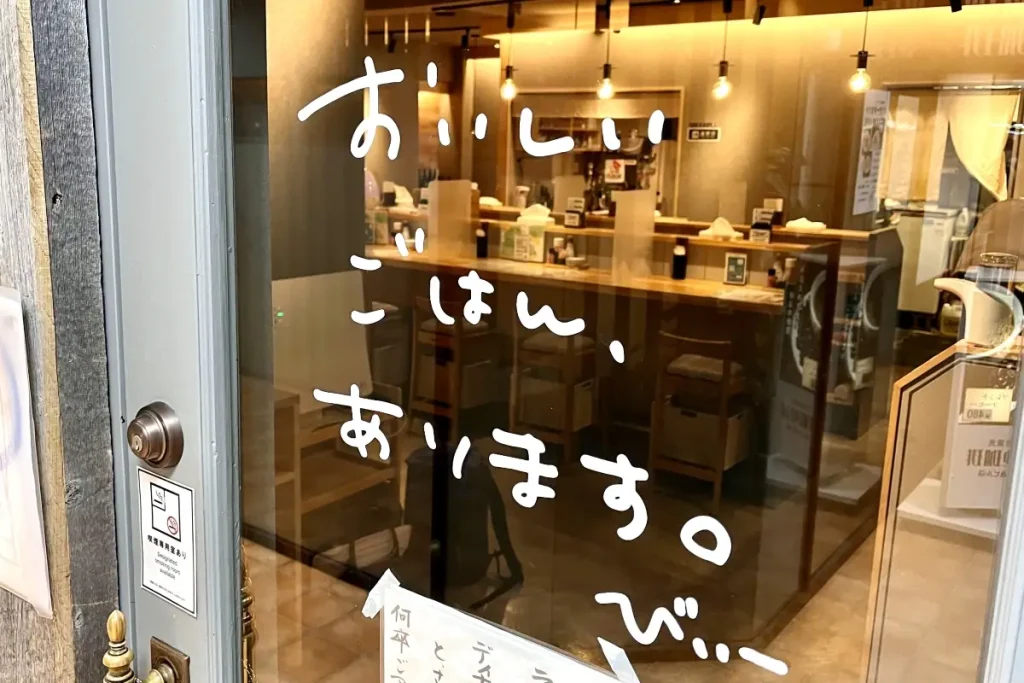 「おいしいごはん、あります」とドアに書かれた「大衆食堂Bee」の店舗入り口