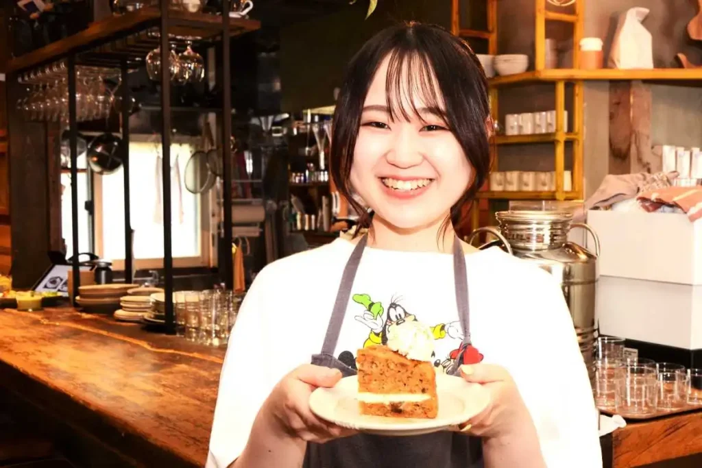 キャロットケーキを持つ店長の三島さん