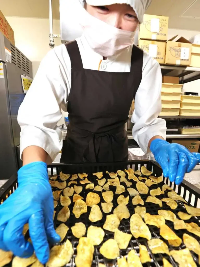 乾燥したチップスに蜜をかけて1枚ずつ並べ、もう一度乾燥させる（加藤哲朗撮影）
