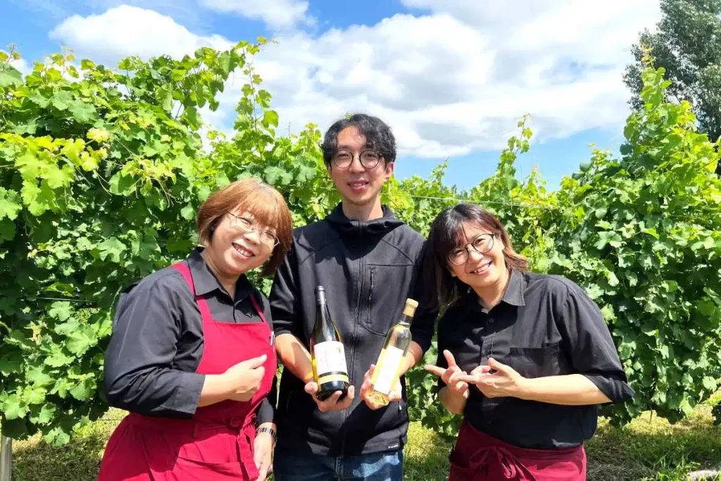販売中の受賞ワインを手にする野吾さん（中央）らワイナリーのスタッフ