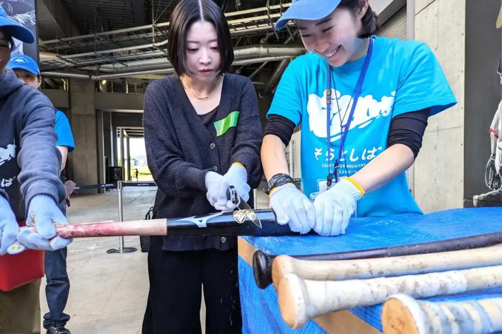 日本ハムの選手たちの折れたバットをのこぎりで切断するファン
