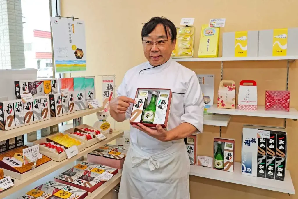 「地酒ケーキ 福司」を手に商品への思いを語る中島徳政代表(小松巧撮影)