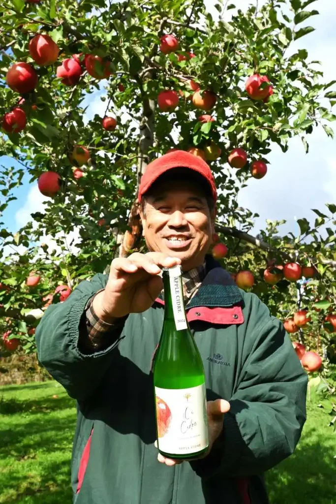 自社の果樹園で採れたリンゴを原料につくったシードルを手に持つ長坂智幸さん